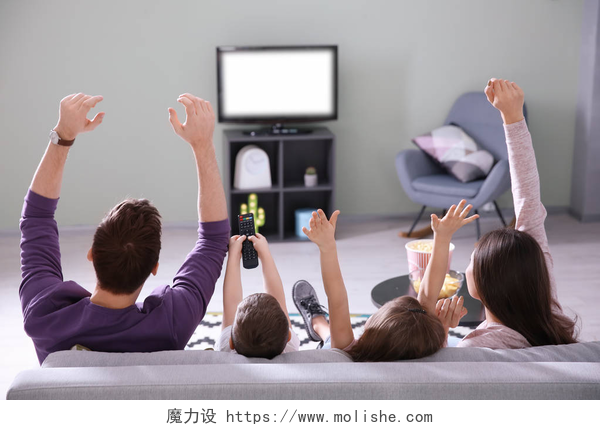 在家庭里看电视的一家四口家庭在家看电视在沙发上